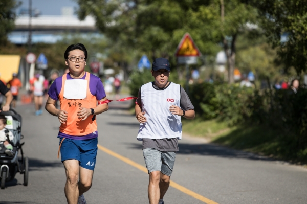지난 12일 여의도 한강시민공원에서 열린 마라톤 행사에서 시각장애인 마라토너와 달리기 도우미인 OCI 직원이 함께 10km를 완주하고 있다. [사진=OCI]
