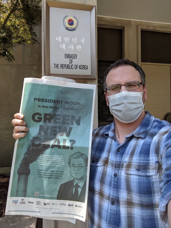 미국 환경단체 활동가가 워싱턴DC 주미한국대사관 앞에서 신문광고를 들고 항의하고 있다. [사진=Oil Change International]