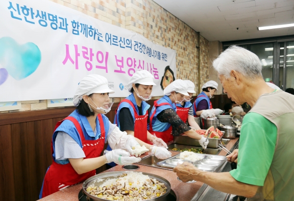 서울 양천어르신종합복지관에서 직원봉사자가 어르신에게 보양식 배식을 하고 있는 모습.(사진=신한생명)